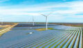 Photo of a windmill in a field with windmills in the back.