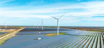 Photo of a windmill in a field with windmills in the back.