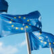 Row of blue EU flags in Brussels. The blue flags have twelve yellow stars depicting the original number of member states.