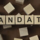 Wooden cubes with word MANDATE on blue table. Cubes with blue letters.