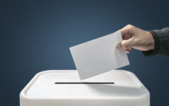 Man putting a ballot paper envelope into a voting box concept for election, freedom and democracy
