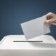 Man putting a ballot paper envelope into a voting box concept for election, freedom and democracy