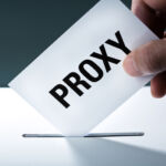 SEC targets small proponents in latest shareholder restriction Voter's hand holding a proxy vote ballot, inserting the vote card into the ballot box.
