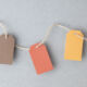 Autumn color palette, blank gift tags with jute twine string on a gray textured surface with copy space.